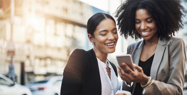 Two young girls smile and look at a mobile together